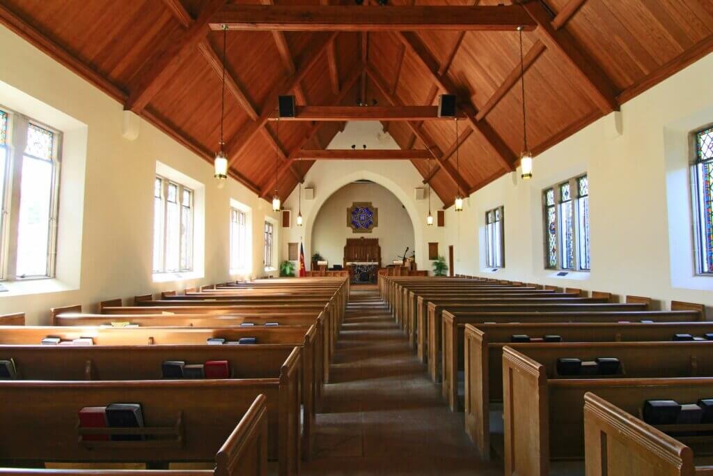 Features a peaceful church interior, with wooden pews and a bright, airy atmosphere. Sunlight streams through stained glass windows, creating a serene space for contemplation and connection to one’s spiritual flow.