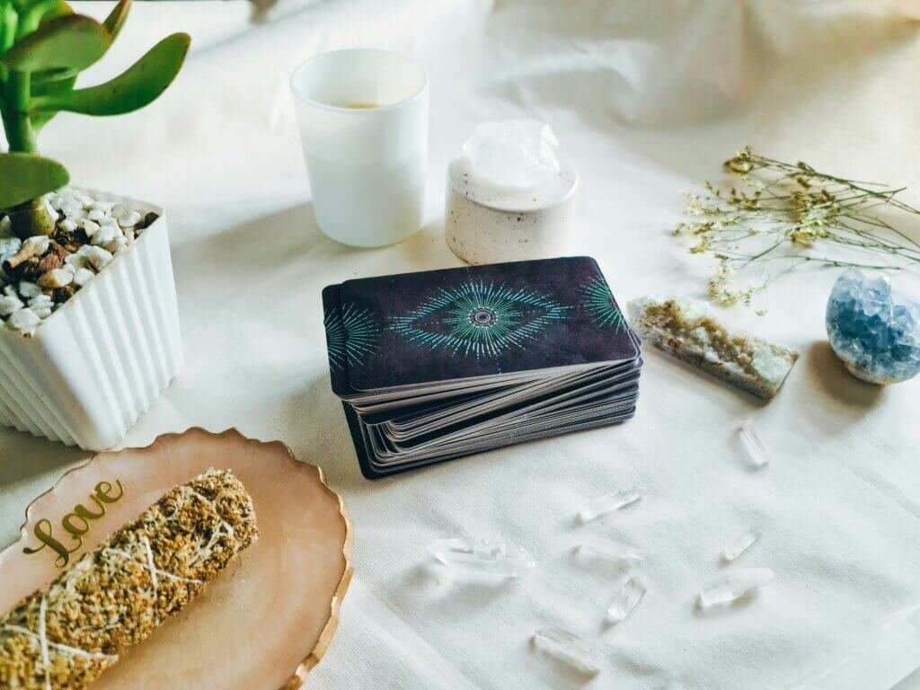 A beautifully arranged altar with a stack of tarot cards, crystals, and plants. It evokes a calming, meditative atmosphere, inviting a connection to intuition and spiritual flow in a modern, relaxed setting.