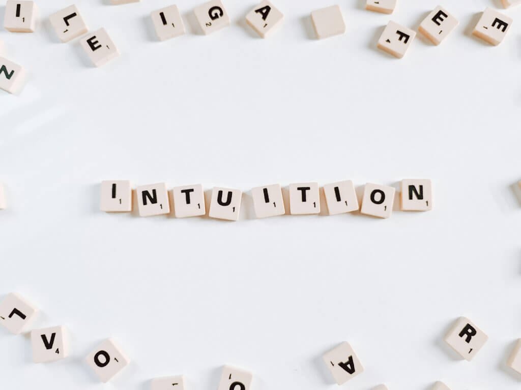 Showcases the word “intuition” spelled out with scrabble tiles, surrounded by scattered letters. It represents the quiet power of intuition and spiritual flow, guiding us even when the world feels a bit chaotic.