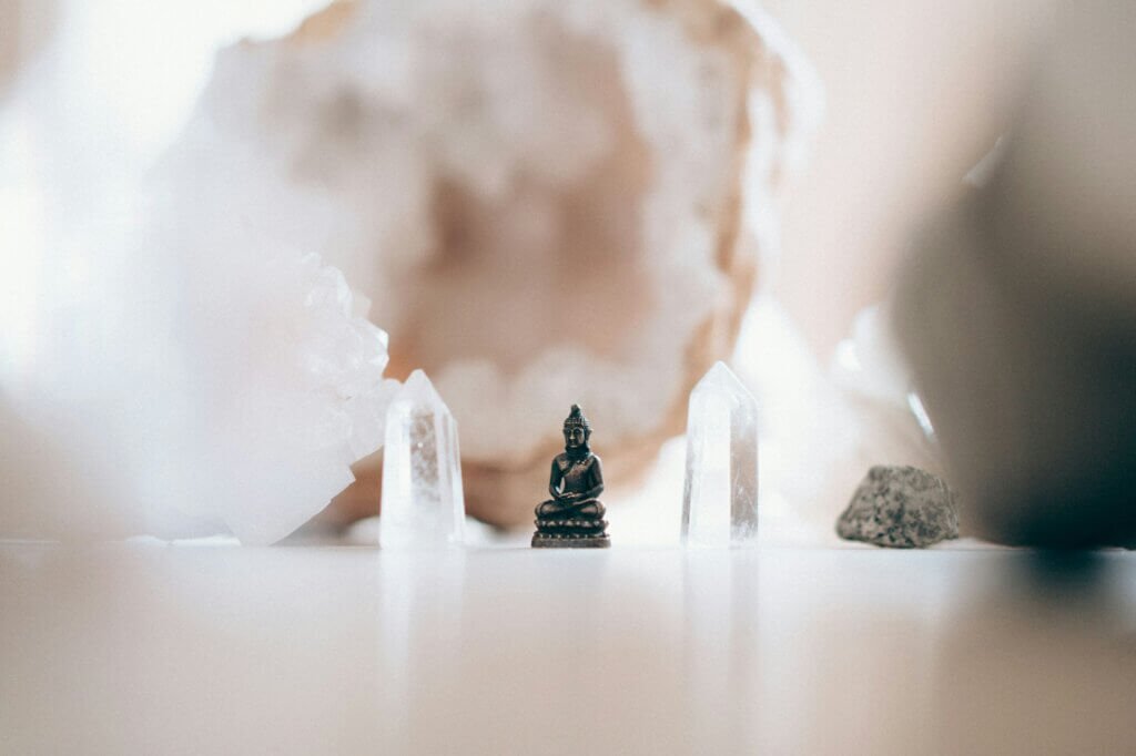 A small buddha statue surrounded by clear crystals, creating a serene, sacred space. The arrangement symbolizes peace, mindfulness, and a deep connection to spiritual flow, highlighting the harmony between stillness and clarity.