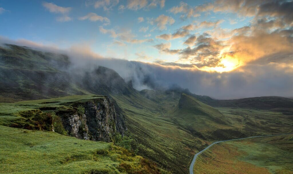 A misty, expansive landscape with a winding road cutting through the green hills. This natural scene evokes a sense of vastness and calm, aligning with the idea of spiritual flow and finding one’s path through the unknown.