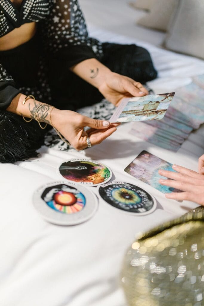 Two people engaging in a tarot and oracle card reading session with colorful cards and spiritual symbols.