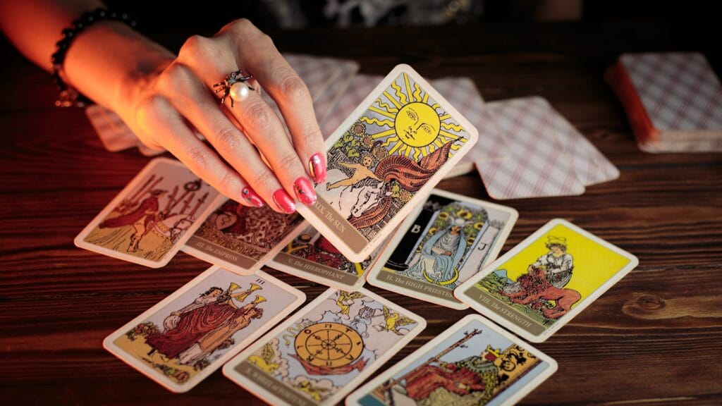 Person holding the sun tarot card, with other tarot cards on the table