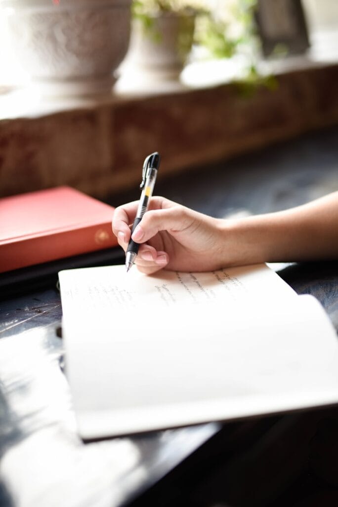 A person writing on a piece of paper with a pen