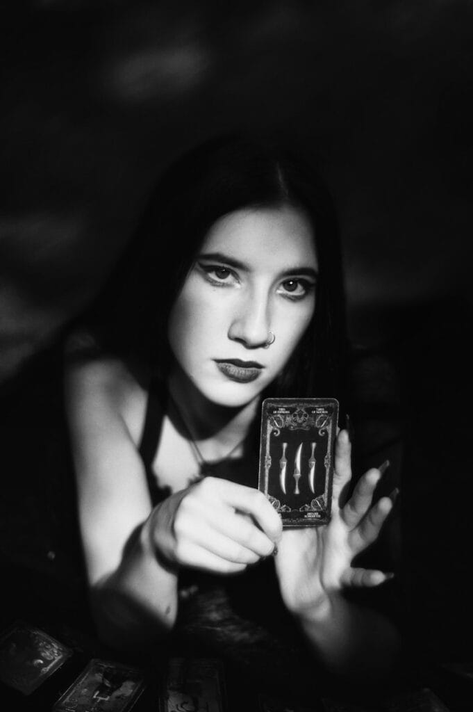 A black and white photo of a woman holding a tarot card