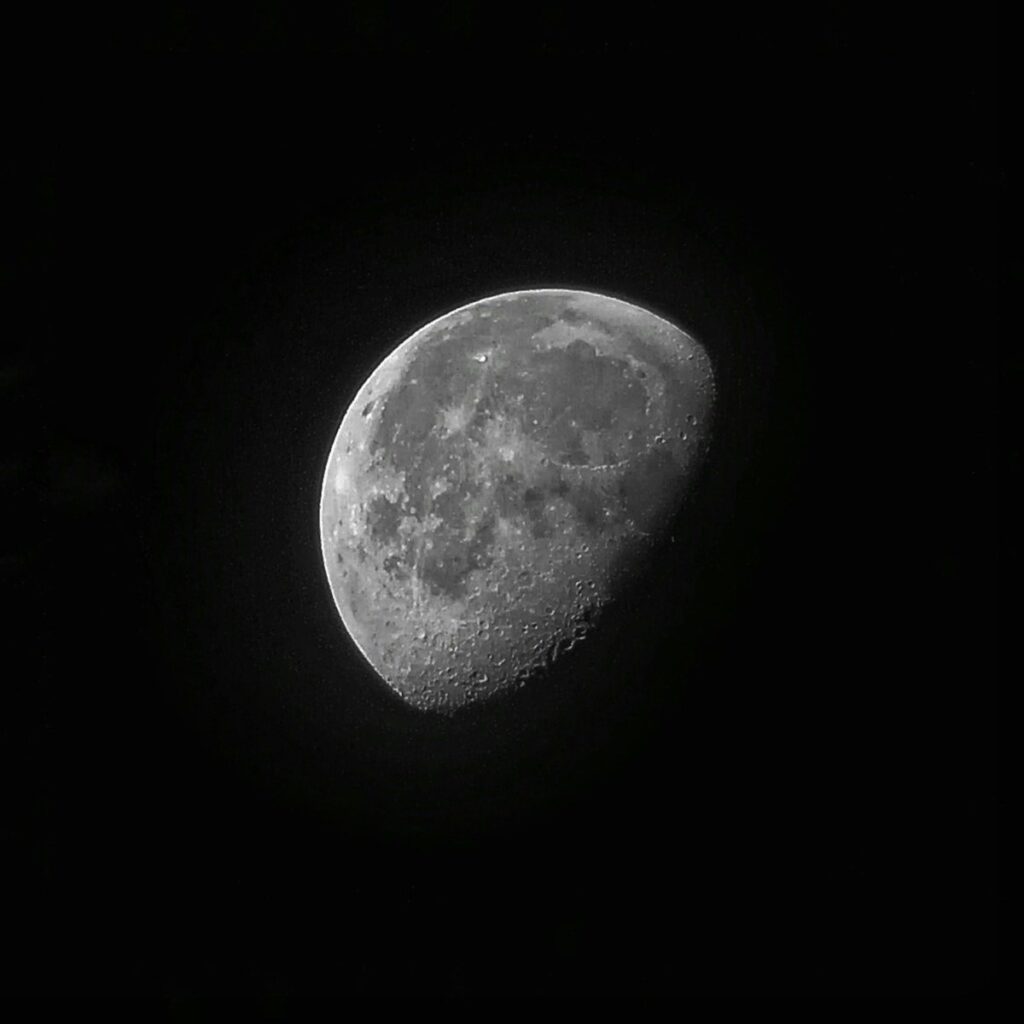 A close up of a waning gibbous in the dark sky